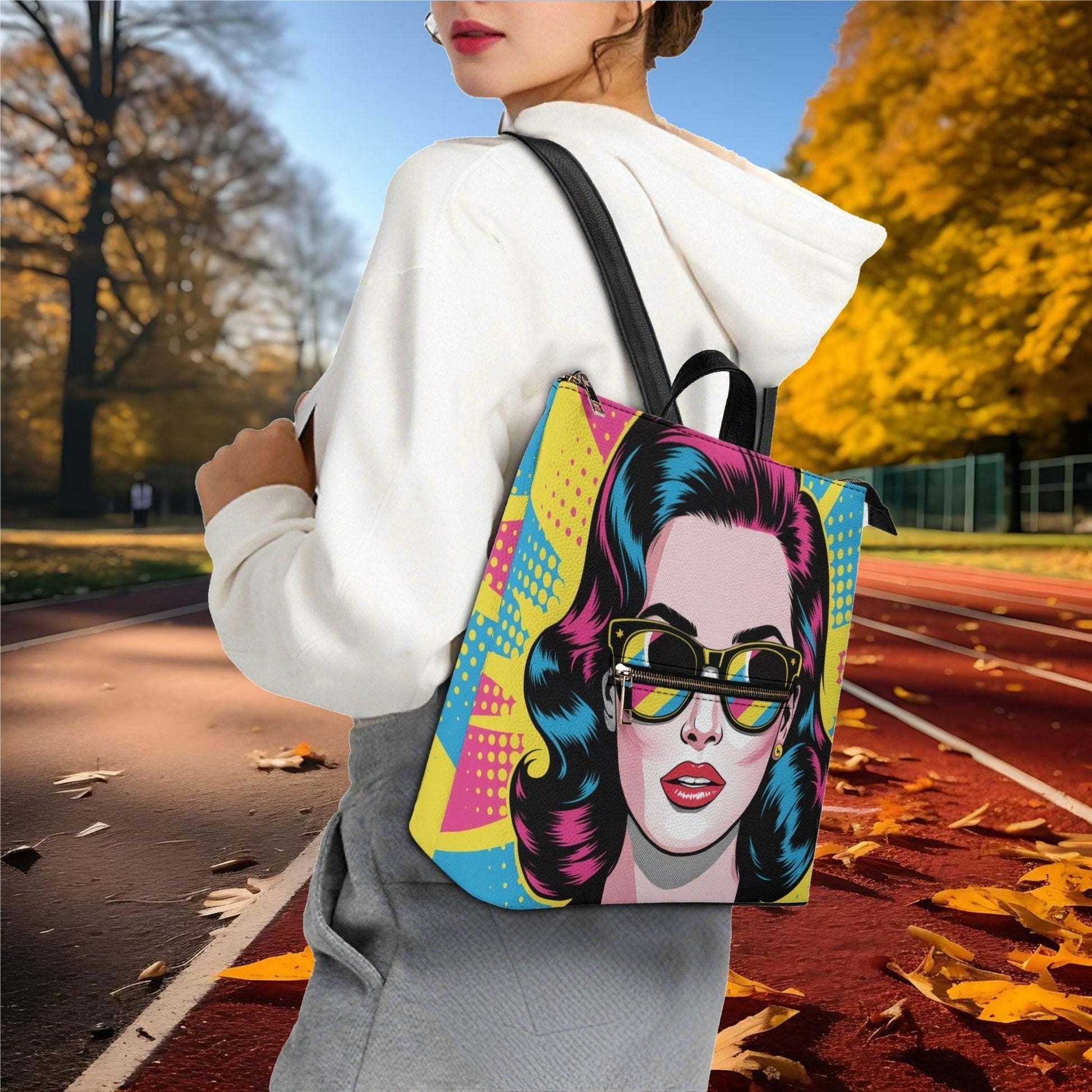 Person holding a colorful backpack with a graphic design of a face wearing sunglasses in an outdoor setting.